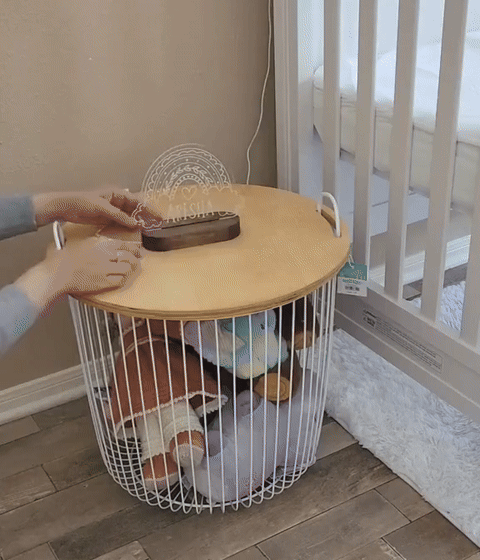 A mother installing a personalized baby night light in the nursery on top of the night table by the crib.