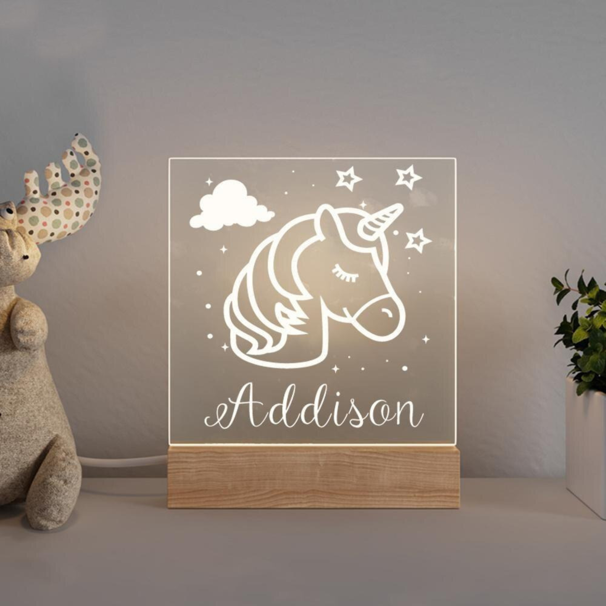 Unicorn personalized night light lit up in a nursery room.
