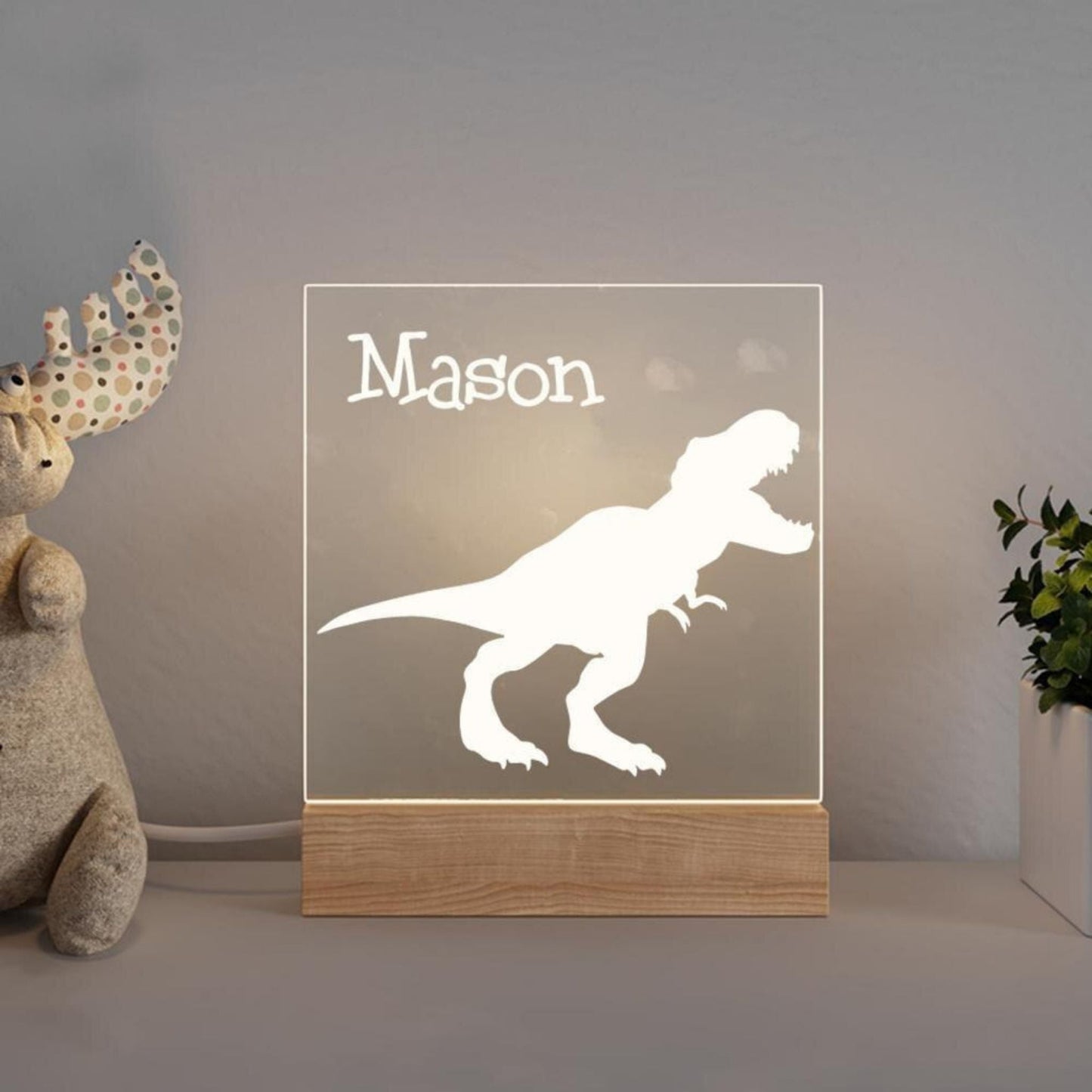 Dinasour themed Personalized Night Light™ with a baby's name on it on a table in nursery.