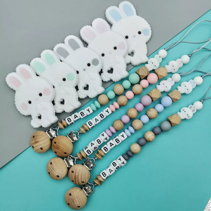 group of five wooden personalized pacifier clips with baby's name and silicone bunny teether for babies