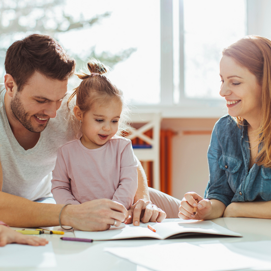 mother and father educating and talking to her little daughter in the dining table doing homework