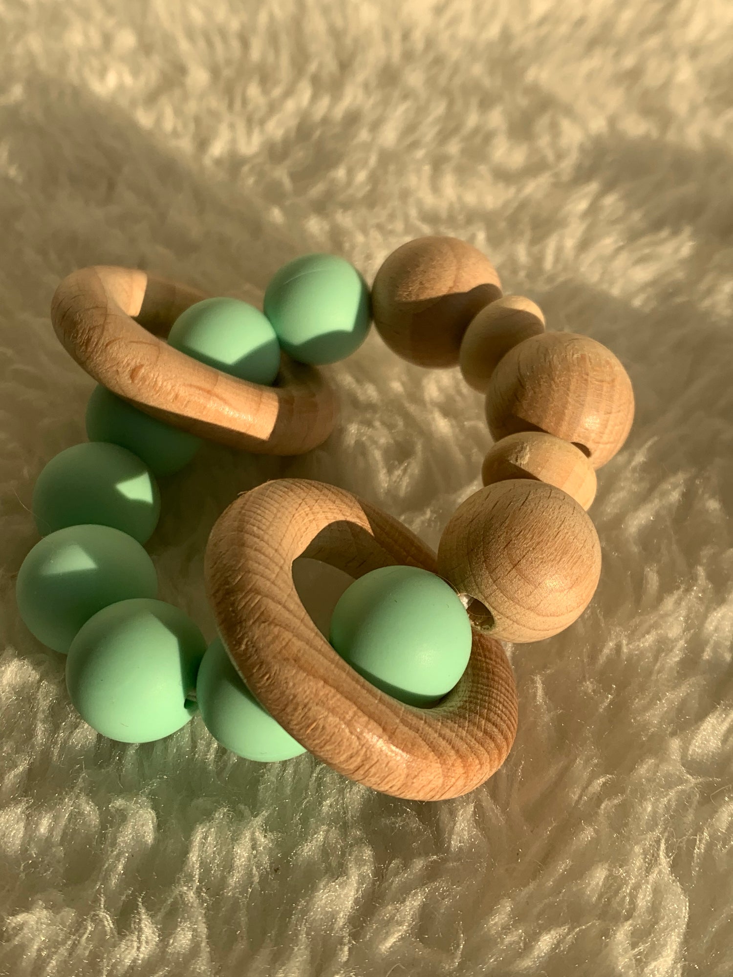 Wooden and silicone beads for a baby rattle on a fur mat
