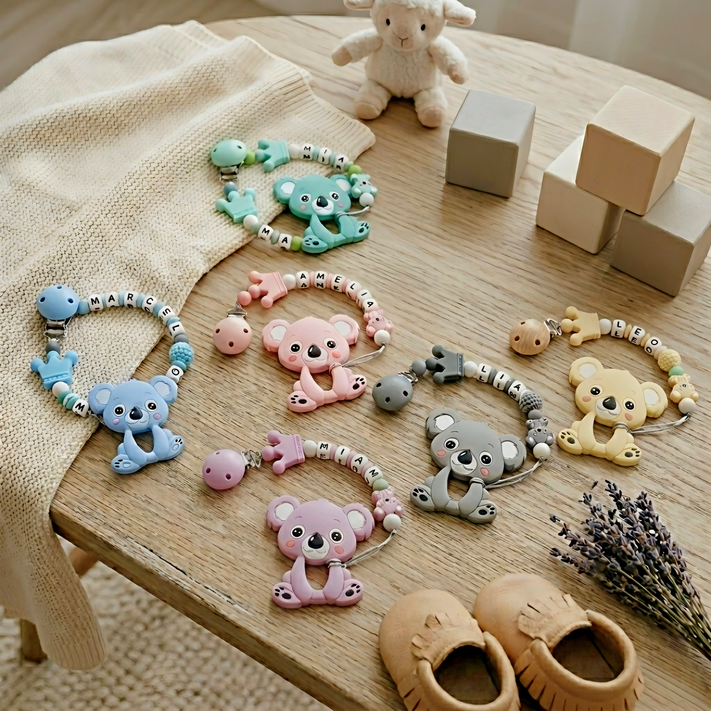 Collection of baby toys and accessories on a wooden surface with blocks and a lamb plush toy.