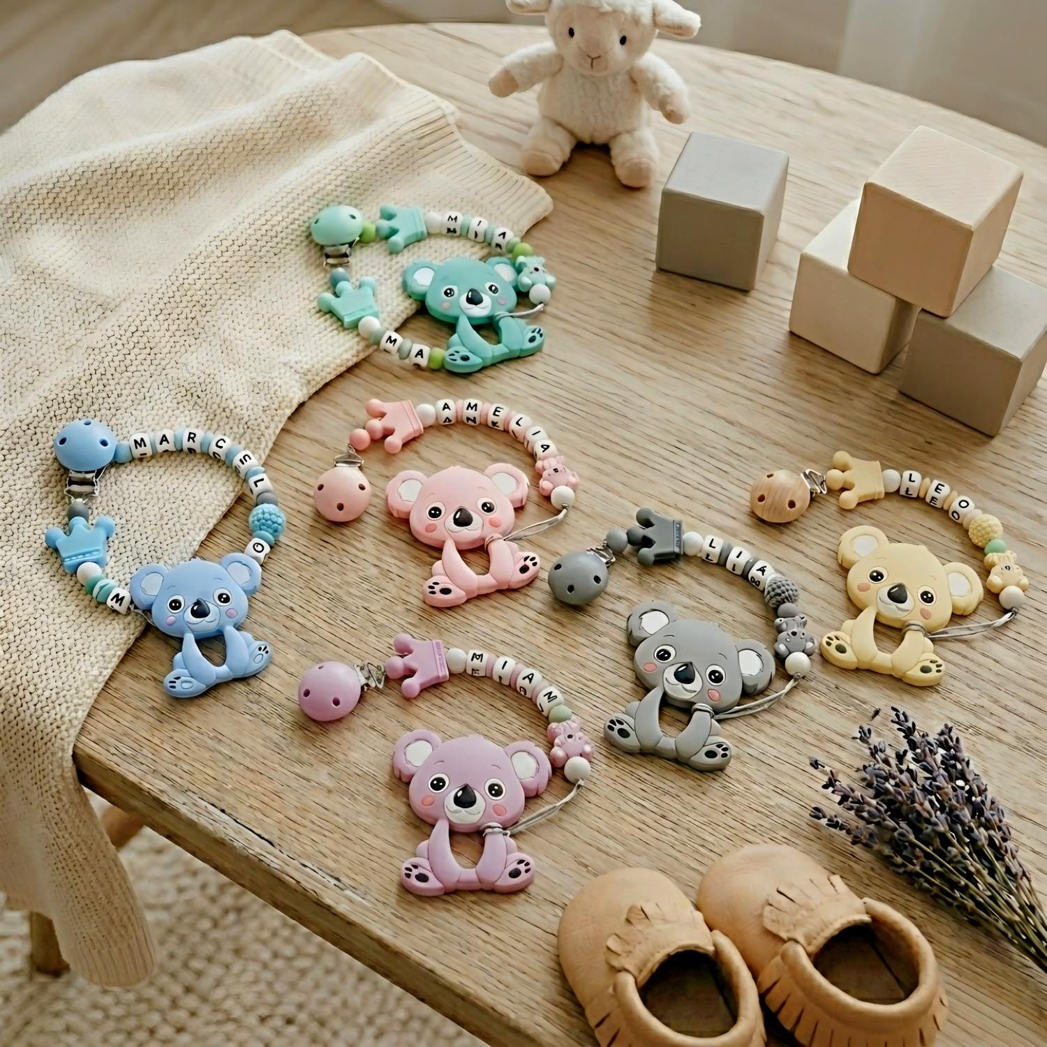 Collection of baby toys and accessories on a wooden surface with blocks and a lamb plush toy.