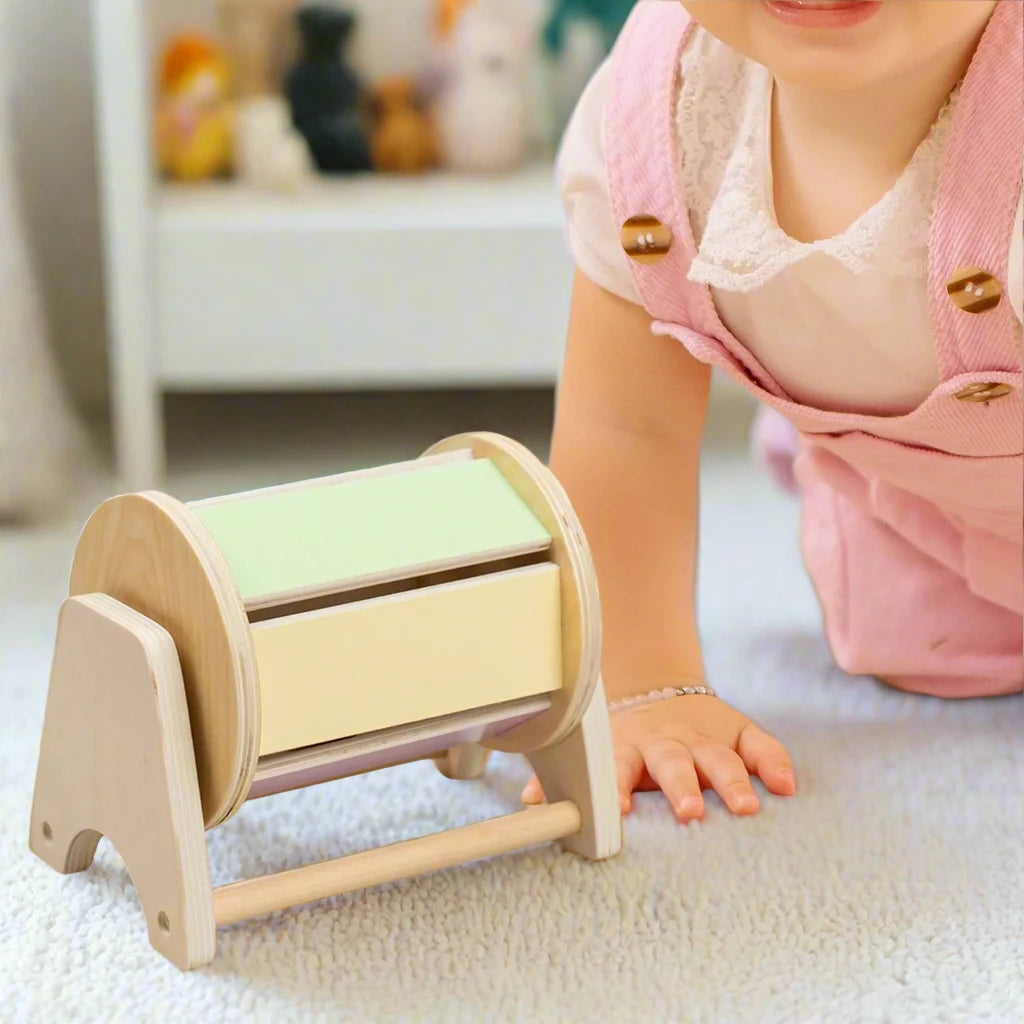 Baby girl playing with wooden Montessori glitter drum