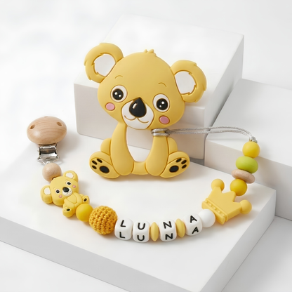 Yellow koala-shaped teether with a customized with baby's name pacifier clip on a white background