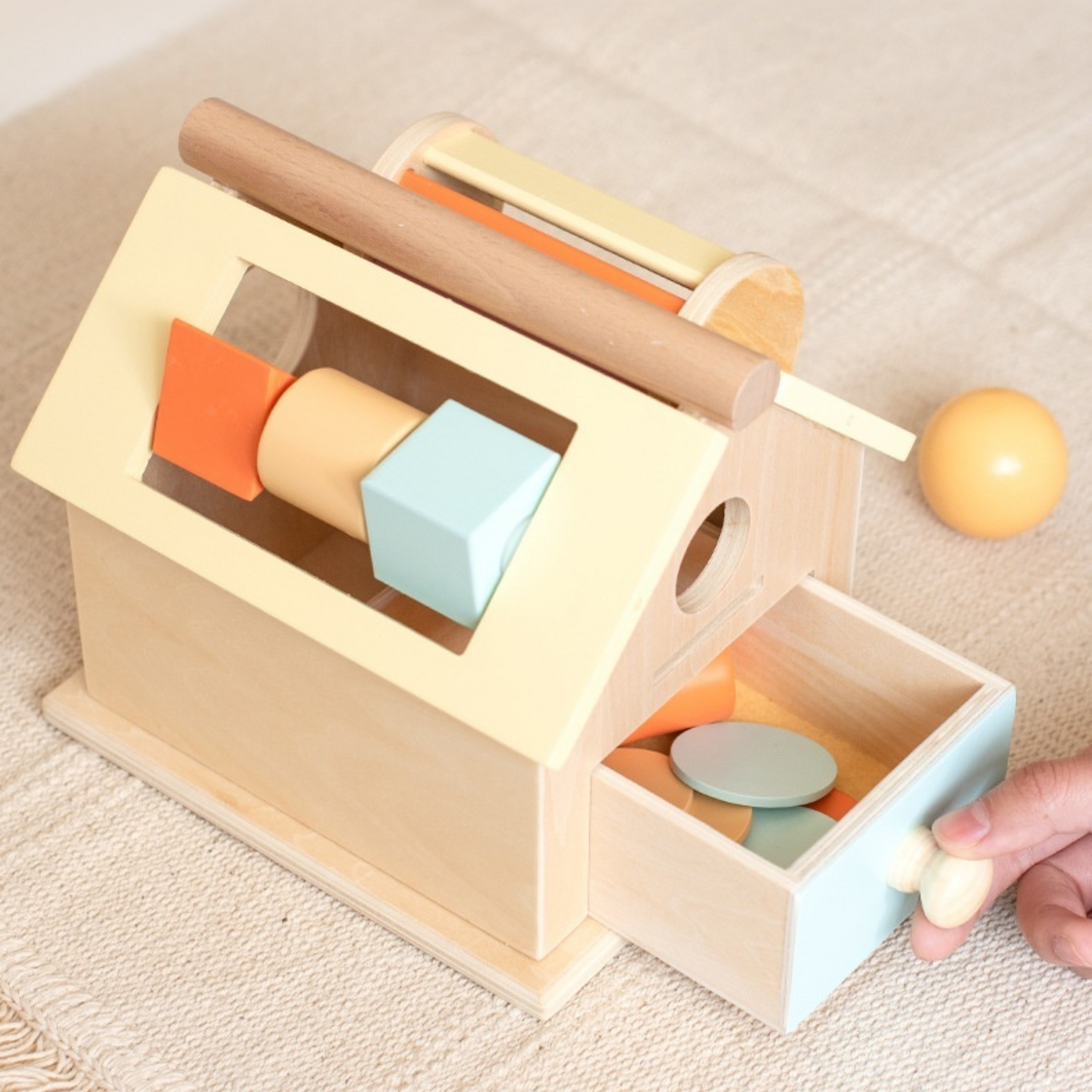 person showing how to use the wooden montessori toy house on the carpet