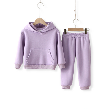 Lilac warm unisex tracksuit for kids and toddlers hung on a hanger against a white wall from hunny bubba kids