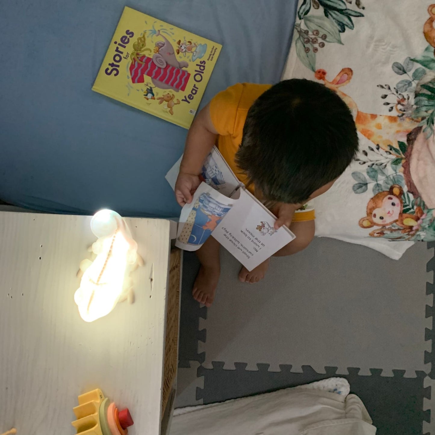 Baby reading a book while using his night lamp to help him read- hunny bubba kids