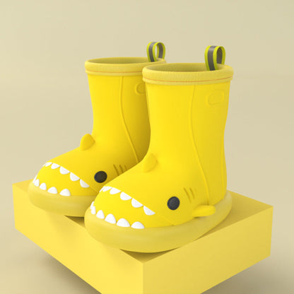 pair of yellow shark rain boots on a yellow block for display