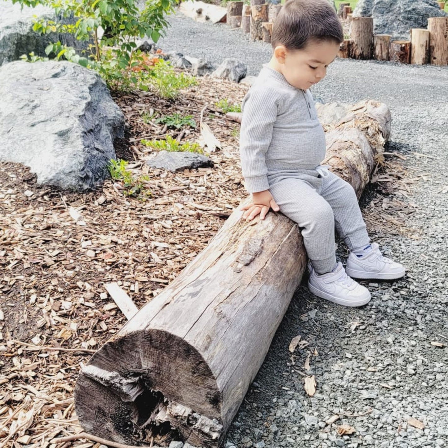 baby sitting down a log wearing an uncisex tracksuit for kids- hunny bubba kids