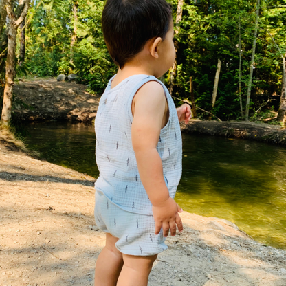 baby walking by the riverbank wearing his unisex bue set